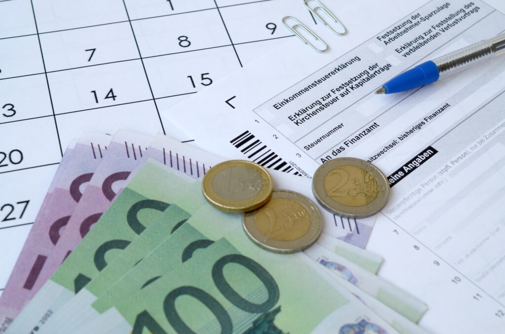 German tax form with pen and european money bills lies on office calendar